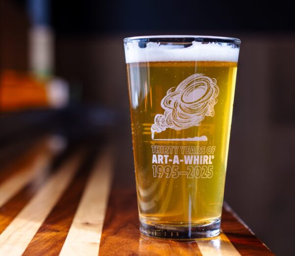 An Art-A-Whirl logo in white text on a beer glass filled with golden ale