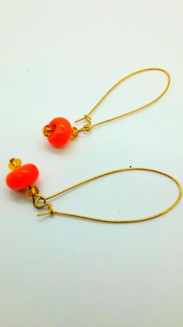 Orange glass beads suspended from gold wire earrings